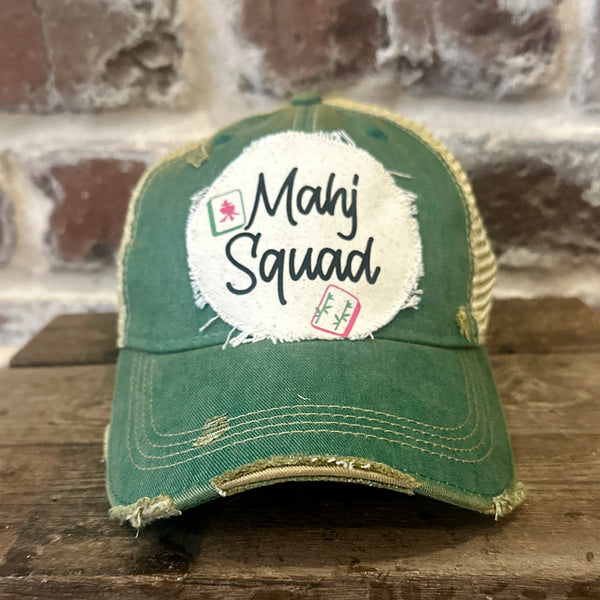 Mahj Squad hat by BohoGroove featuring black Mahj Squad lettering with Mahjong tile graphics on an off-white distressed patch on a green vintage distressed snapback trucker hat.