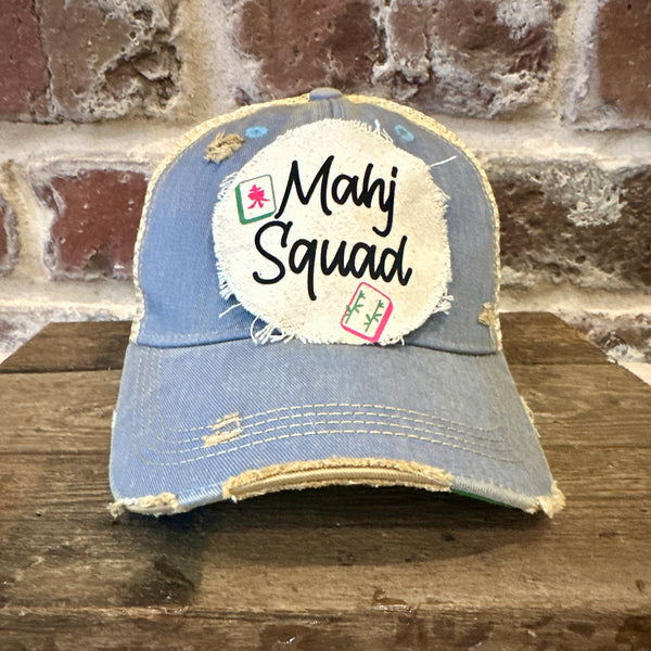 Mahj Squad hat by BohoGroove featuring black Mahj Squad lettering with Mahjong tile graphics on an off-white distressed patch on a light blue vintage distressed snapback trucker hat.