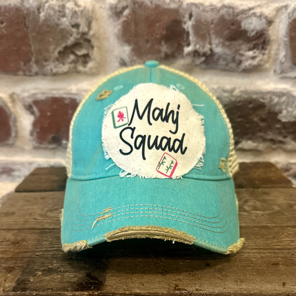 Mahj Squad hat by BohoGroove featuring black Mahj Squad lettering with Mahjong tile graphics on an off-white distressed patch on an ocean blue vintage distressed snapback trucker hat.
