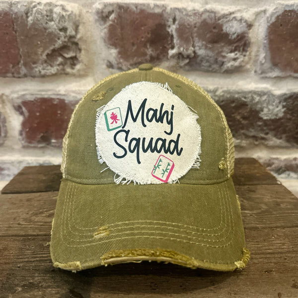 Mahj Squad hat by BohoGroove featuring black Mahj Squad lettering with Mahjong tile graphics on an off-white distressed patch on an olive vintage distressed snapback trucker hat.