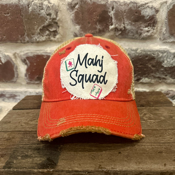 Mahj Squad hat by BohoGroove featuring black Mahj Squad lettering with Mahjong tile graphics on an off-white distressed patch on a red vintage distressed snapback trucker hat.