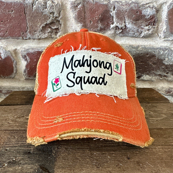 Mahjong Squad hat by BohoGroove featuring black Mahjong Squad lettering with Mahjong tile graphics on an off-white distressed patch on an orange vintage distressed snapback trucker hat.