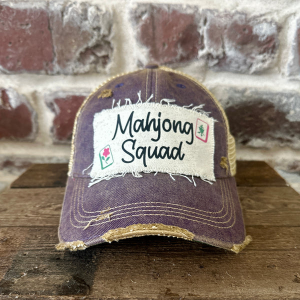 Mahjong Squad hat by BohoGroove featuring black Mahjong Squad lettering with Mahjong tile graphics on an off-white distressed patch on a purple vintage distressed snapback trucker hat.