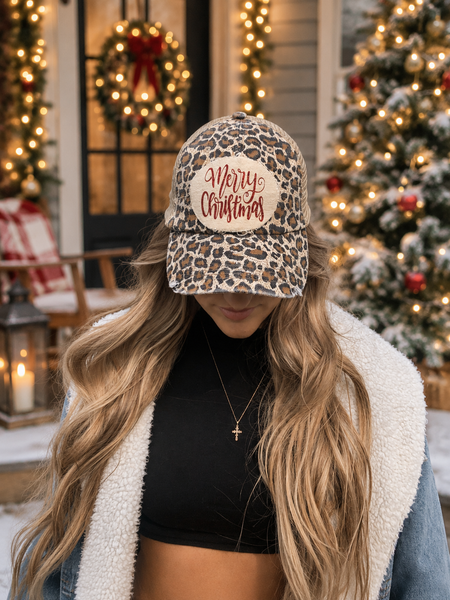 Merry Christmas Glitter hat by BohoGroove with red glitter Merry Christmas script lettering on a distressed off-white custom patch on a leopard vintage distressed snapback on model.