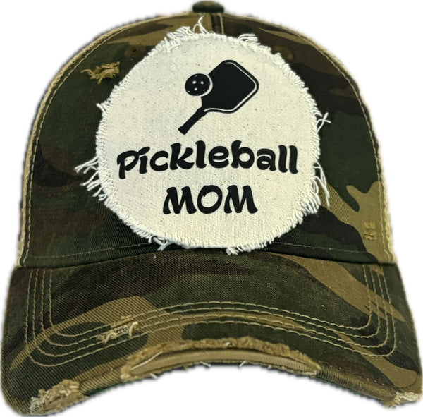 Pickleball Mom hat by BohoGroove featuring black Pickleball Mom lettering and black pickleball paddle graphic on a camo vintage distressed snapback hat