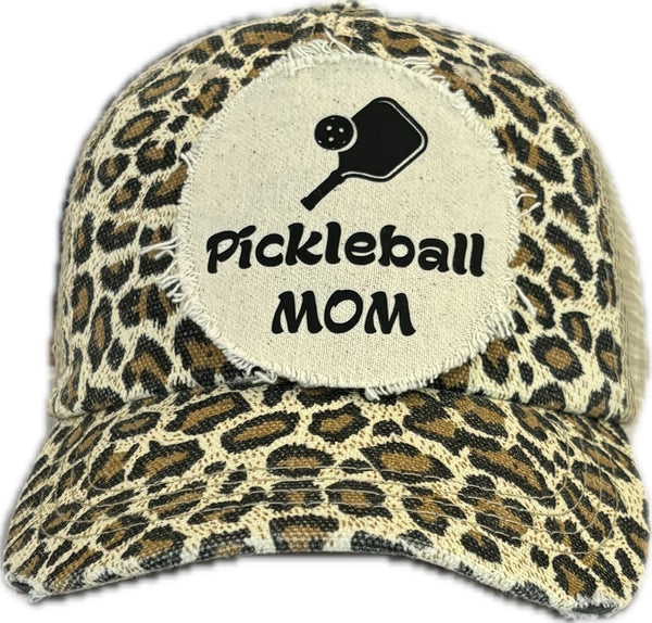 Pickleball Mom hat by BohoGroove featuring black Pickleball Mom lettering and black pickleball paddle graphic on a leopard vintage distressed snapback hat