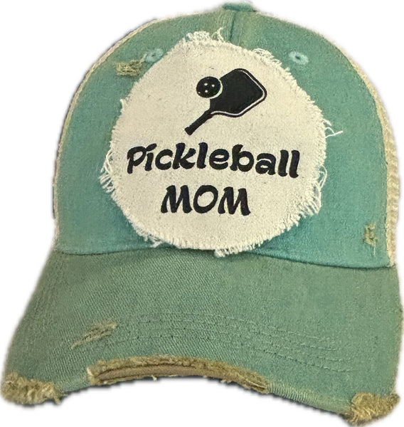 Pickleball Mom hat by BohoGroove featuring black Pickleball Mom lettering and black pickleball paddle graphic on an ocean blue vintage distressed snapback hat