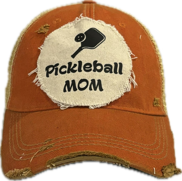 Pickleball Mom hat by BohoGroove featuring black Pickleball Mom lettering and black pickleball paddle graphic on an orange vintage distressed snapback hat