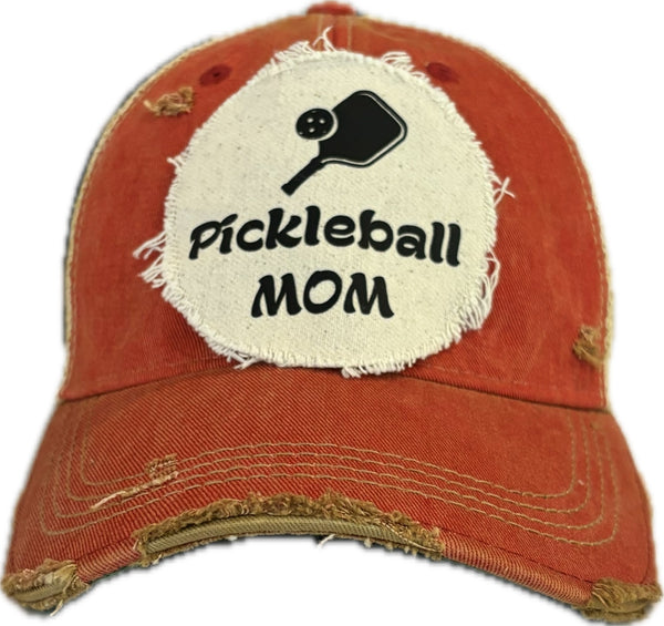 Pickleball Mom hat by BohoGroove featuring black Pickleball Mom lettering and black pickleball paddle graphic on a red vintage distressed snapback hat