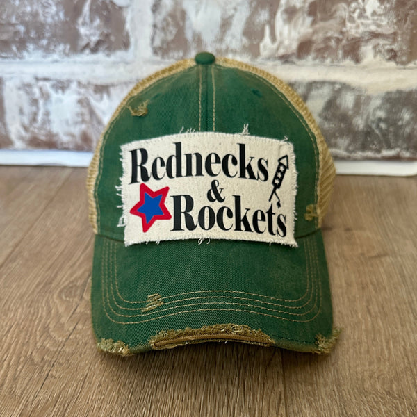 Rednecks And Rockets hat by BohoGroove with black lettering, red and blue star graphic, and firework rocket graphic on distressed off-white patch on green vintage distressed snapback.