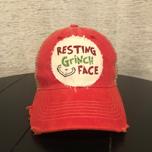 Resting Grinch Face hat by BohoGroove with red and green Resting Grinch Face lettering and Grinch-inspired face graphic on a distressed off-white custom patch on a red vintage distressed snapback.