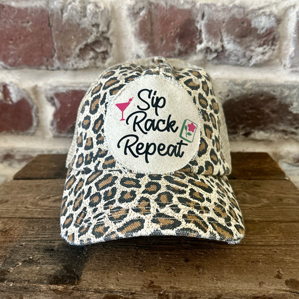 Sip, Rack, Repeat Mahjong hat by BohoGroove featuring black Sip, Rack, Repeat lettering with Mahjong tile graphic and a pink martini glass on an off-white distressed patch on a leopard vintage distressed snapback trucker hat.