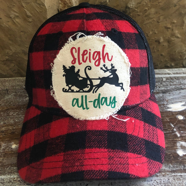 Sleigh All Day hat by BohoGroove with red Sleigh lettering, green all-day lettering, and black Santa sleigh and reindeer graphics on a distressed off-white patch on a red and black buffalo plaid snapback trucker hat.
