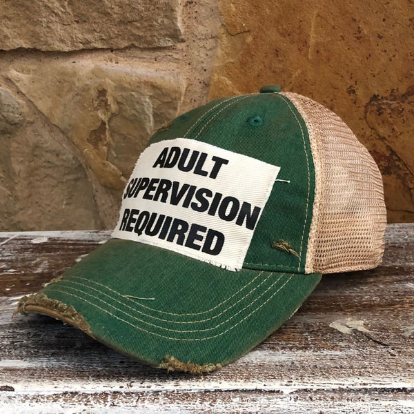 Right side view of the Adult Supervision Required hat by BohoGroove with black lettering on a distressed off-white patch on a green vintage distressed snapback trucker hat.