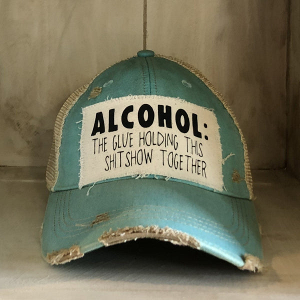 Alcohol: The Glue Holding This Shitshow Together hat by BohoGroove with black lettering on a distressed off-white patch on an ocean blue vintage distressed snapback trucker hat.
