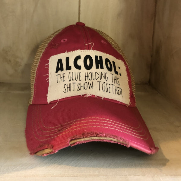 Alcohol: The Glue Holding This Shitshow Together hat by BohoGroove with black lettering on a distressed off-white patch on a pink vintage distressed snapback trucker hat.