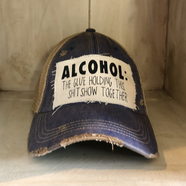 Alcohol: The Glue Holding This Shitshow Together hat by BohoGroove with black lettering on a distressed off-white patch on a royal blue vintage distressed snapback trucker hat.