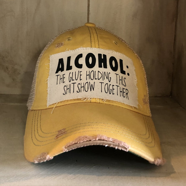 Alcohol: The Glue Holding This Shitshow Together hat by BohoGroove with black lettering on a distressed off-white patch on a yellow vintage distressed snapback trucker hat.