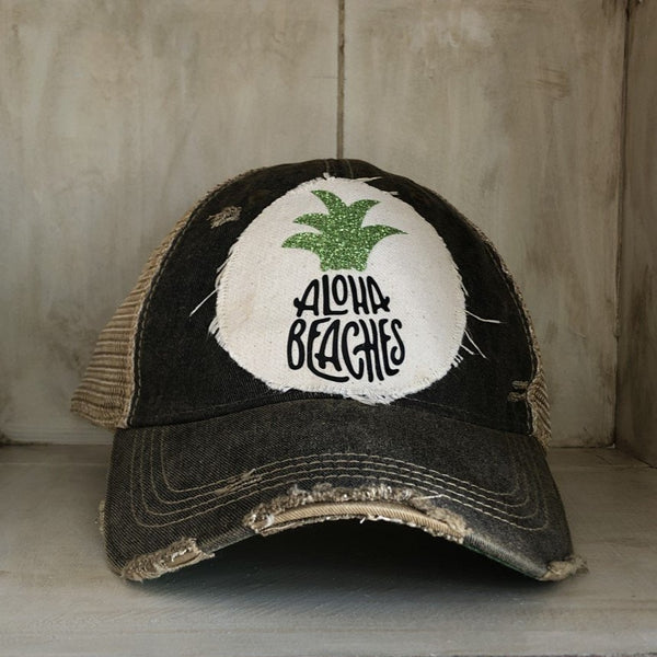 Aloha Beaches hat by BohoGroove with black Aloha Beaches lettering and green pineapple graphic on distressed off-white patch and black vintage distressed snapback.