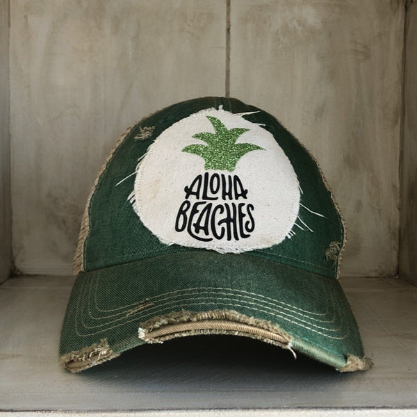 Aloha Beaches hat by BohoGroove with black Aloha Beaches lettering and green pineapple graphic on distressed off-white patch and green vintage distressed snapback.