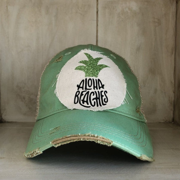 Aloha Beaches hat by BohoGroove with black Aloha Beaches lettering and green pineapple graphic on distressed off-white patch and mint green vintage distressed snapback.