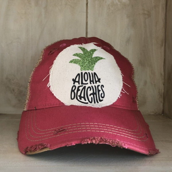 Aloha Beaches hat by BohoGroove with black Aloha Beaches lettering and green pineapple graphic on distressed off-white patch and pink vintage distressed snapback.