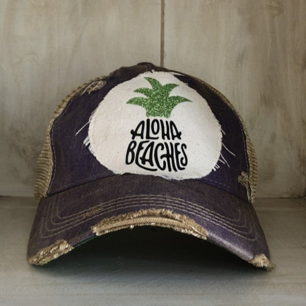 Aloha Beaches hat by BohoGroove with black Aloha Beaches lettering and green pineapple graphic on distressed off-white patch and purple vintage distressed snapback.