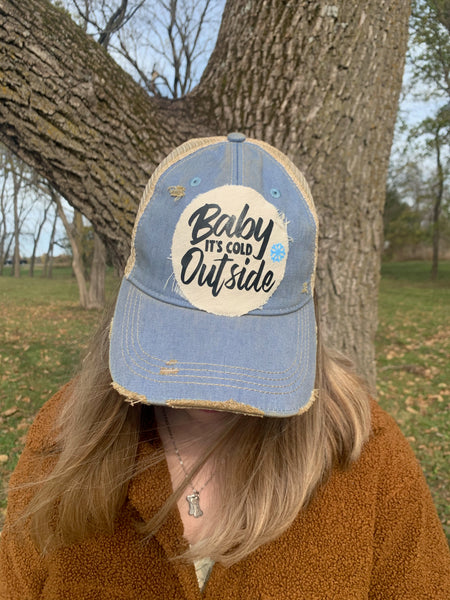 Baby It's Cold Outside hat by BohoGroove with black script lettering and a blue snowflake graphic on a distressed off-white custom patch on a light blue vintage distressed snapback on model.
