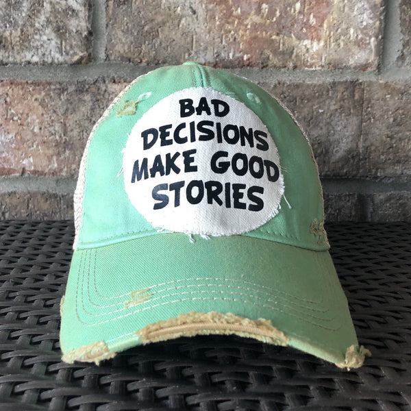 Bad Decisions Make Good Stories hat by BohoGroove with black Bad Decisions Make Good Stories lettering on a distressed off-white patch on a mint vintage distressed snapback trucker hat.