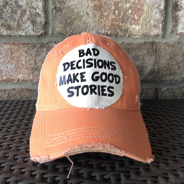 Bad Decisions Make Good Stories hat by BohoGroove with black Bad Decisions Make Good Stories lettering on a distressed off-white patch on a sherbet vintage distressed snapback trucker hat.