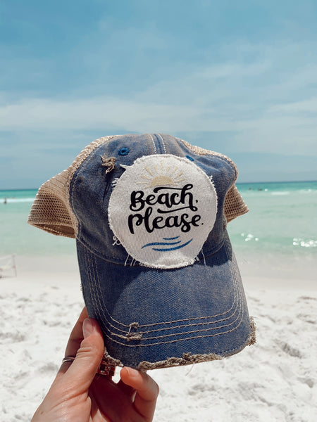 Beach Please hat by BohoGroove with black Beach Please lettering, sun graphic, and blue wave graphic on distressed off-white patch and blue vintage distressed snapback photographed at the beach.