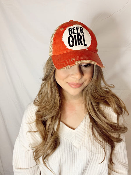 Woman wearing a Beer Girl hat by BohoGroove with black Beer Girl lettering on a distressed off-white patch on a brick red vintage distressed snapback trucker hat.