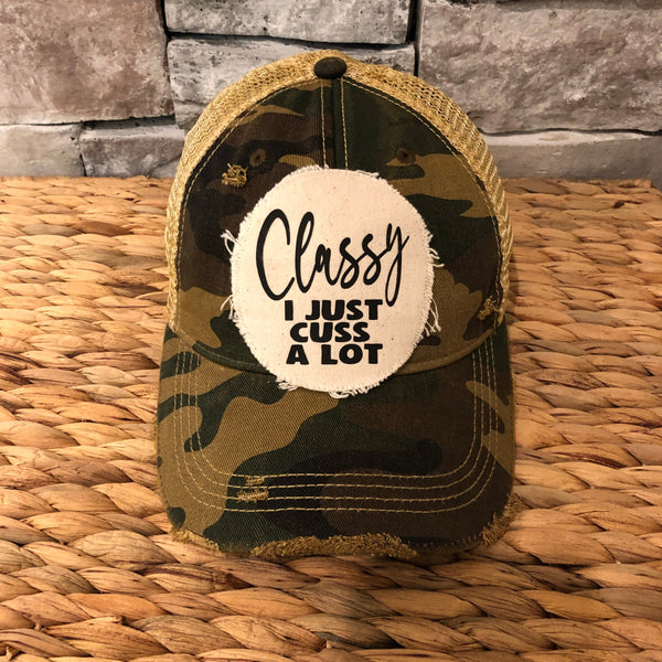 Classy, I Just Cuss a Lot hat by BohoGroove with black lettering on a distressed off-white patch on a camo vintage distressed snapback trucker hat.