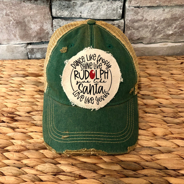 Dance Like Frosty Shine Like Rudolph Give Like Santa Love Like Jesus hat by BohoGroove with red and green lettering and Christmas phrase on a distressed off-white patch on a green vintage distressed snapback.