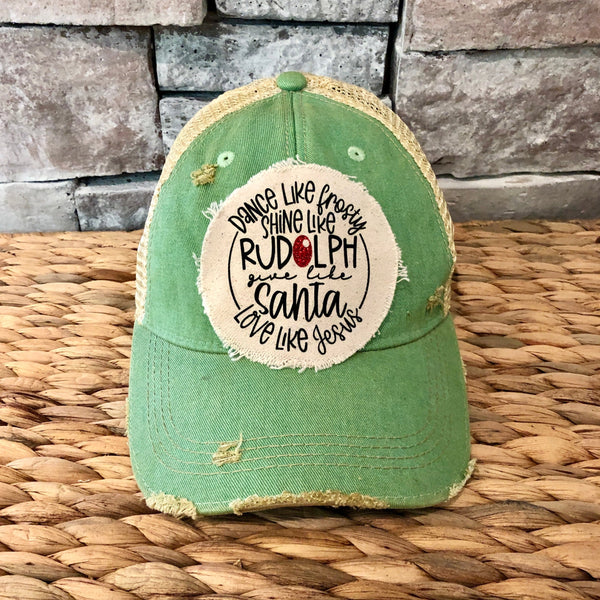 Dance Like Frosty Shine Like Rudolph Give Like Santa Love Like Jesus hat by BohoGroove with red and green lettering and Christmas phrase on a distressed off-white patch on a mint vintage distressed snapback.