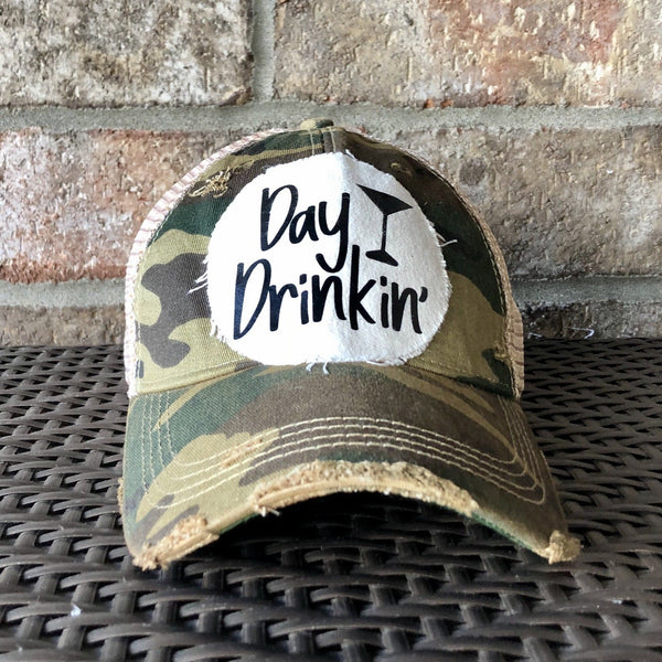 Day Drinkin hat by BohoGroove with black Day Drinkin lettering and martini glass graphic on distressed off-white patch on a camo vintage distressed snapback.