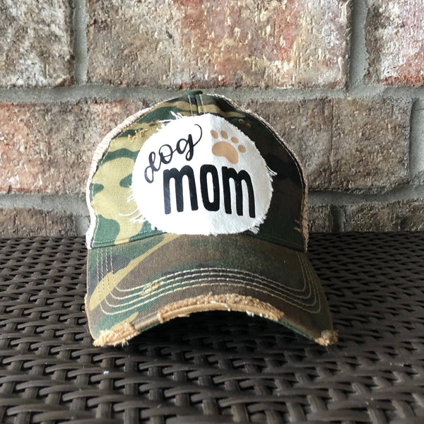 Dog Mom hat by BohoGroove featuring black Dog Mom lettering and tan paw print graphic on a camo vintage distressed snapback hat