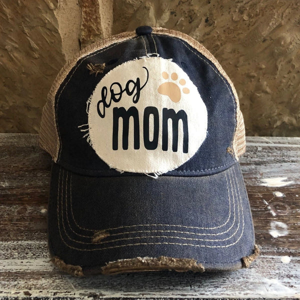 Dog Mom hat by BohoGroove featuring black Dog Mom lettering and tan paw print graphic on a navy blue vintage distressed snapback hat
