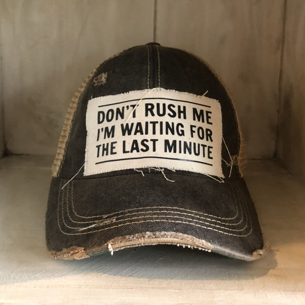 Don't Rush Me I'm Waiting for the Last Minute hat by BohoGroove with black lettering on a distressed off-white patch on a black vintage distressed snapback trucker hat.