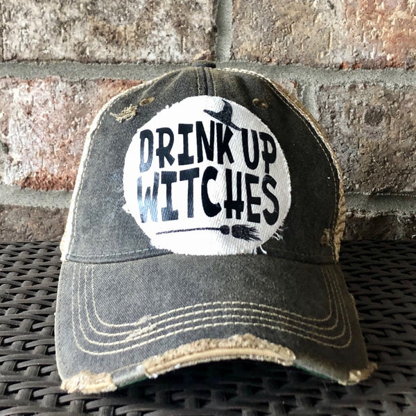 Drink Up Witches hat by BohoGroove with black Drink Up Witches lettering, witch hat graphic and broom graphic on a distressed off-white patch on a black vintage distressed snapback.