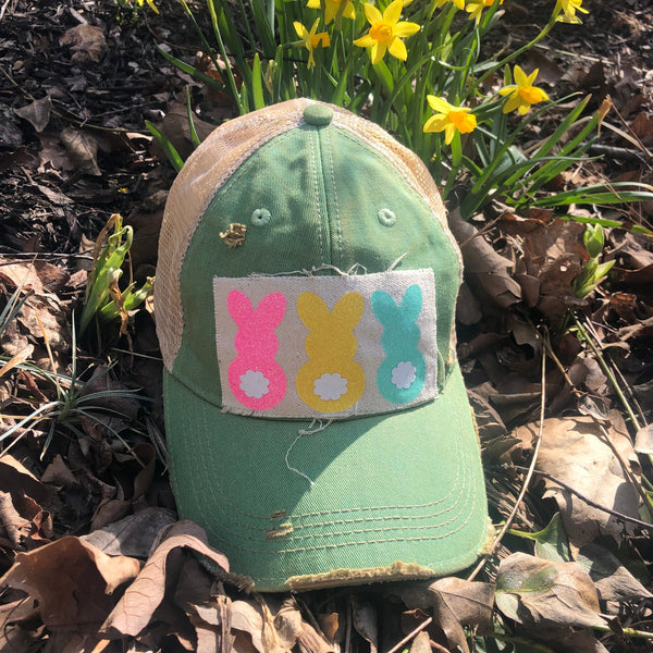 Easter Bunny hat by BohoGroove with pink, yellow, and mint bunny graphics with white flower accents on distressed off-white patch on a mint vintage distressed snapback.