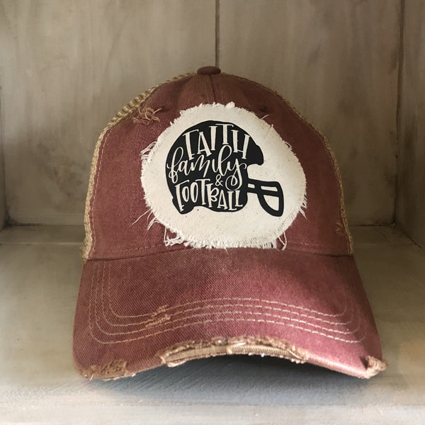 Faith Family & Football hat by BohoGroove with black Faith Family & Football lettering and football helmet graphic on a distressed off-white patch on a brick red vintage distressed snapback.