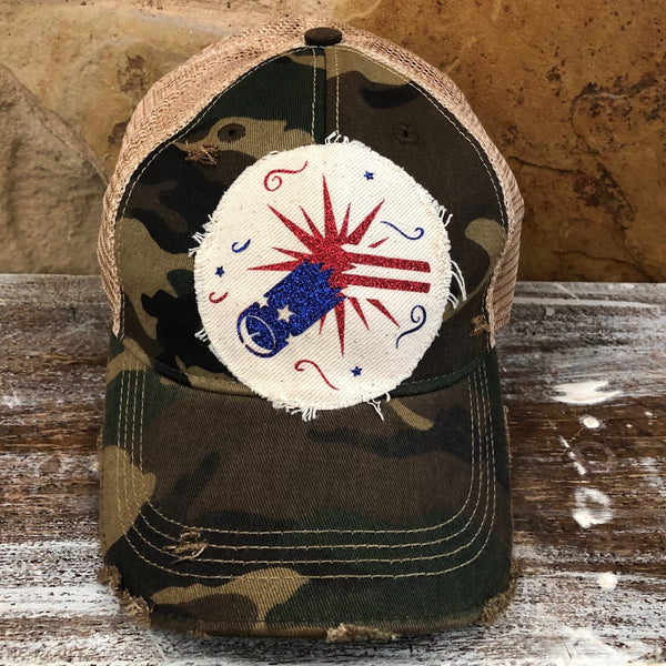 Firework hat by BohoGroove featuring blue glitter firework cannon, red firework burst, and patriotic stars on distressed off-white patch and camo vintage distressed snapback