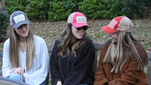 Three women wearing BohoGroove vintage distressed snapback hats while sitting outdoors