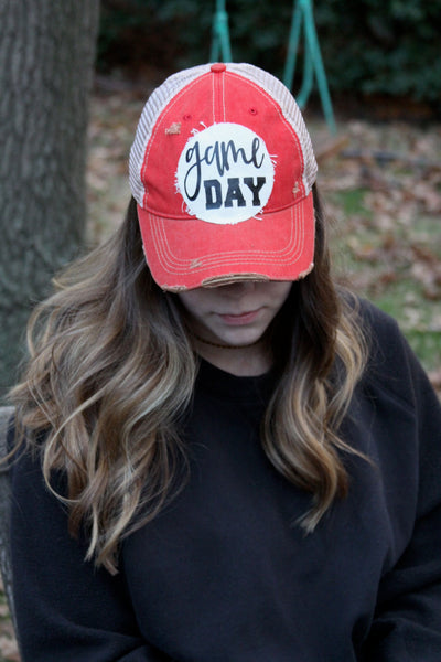 Girl wearing a red BohoGroove game day hat looking down