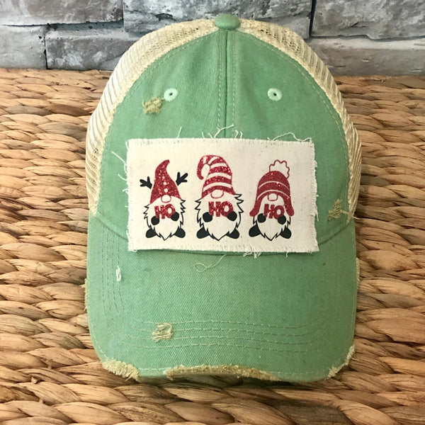 Gnome Ho Ho Ho hat by BohoGroove with three Christmas gnomes wearing red glitter hats and Ho Ho Ho lettering on a distressed off-white patch on a mint vintage distressed snapback.