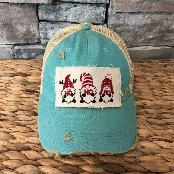 Gnome Ho Ho Ho hat by BohoGroove with three Christmas gnomes wearing red glitter hats and Ho Ho Ho lettering on a distressed off-white patch on an ocean blue vintage distressed snapback.
