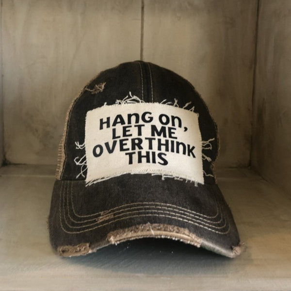 Hang On Let Me Overthink This hat by BohoGroove with black Hang On Let Me Overthink This lettering on a distressed off-white patch on a black vintage distressed snapback trucker hat.