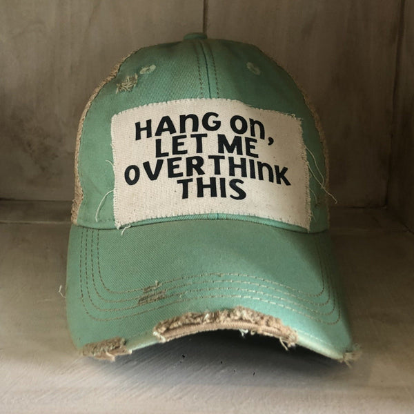 Hang On Let Me Overthink This hat by BohoGroove with black Hang On Let Me Overthink This lettering on a distressed off-white patch on a mint vintage distressed snapback trucker hat.