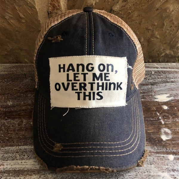 Hang On Let Me Overthink This hat by BohoGroove with black Hang On Let Me Overthink This lettering on a distressed off-white patch on a navy blue vintage distressed snapback trucker hat.